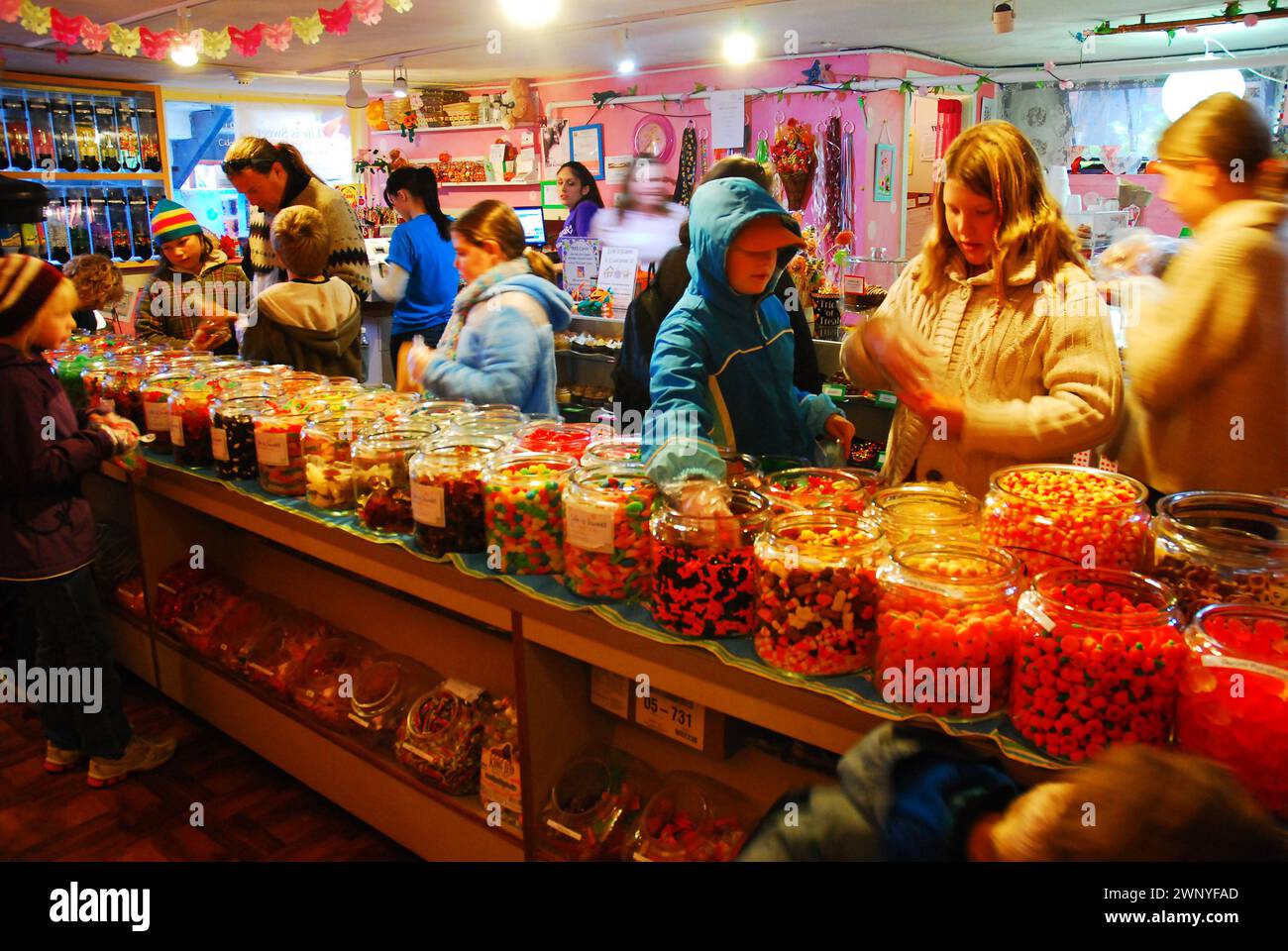 Les enfants et leurs parents se rassemblent autour de pots de bonbons dans un magasin de bonbons à l'ancienne Banque D'Images