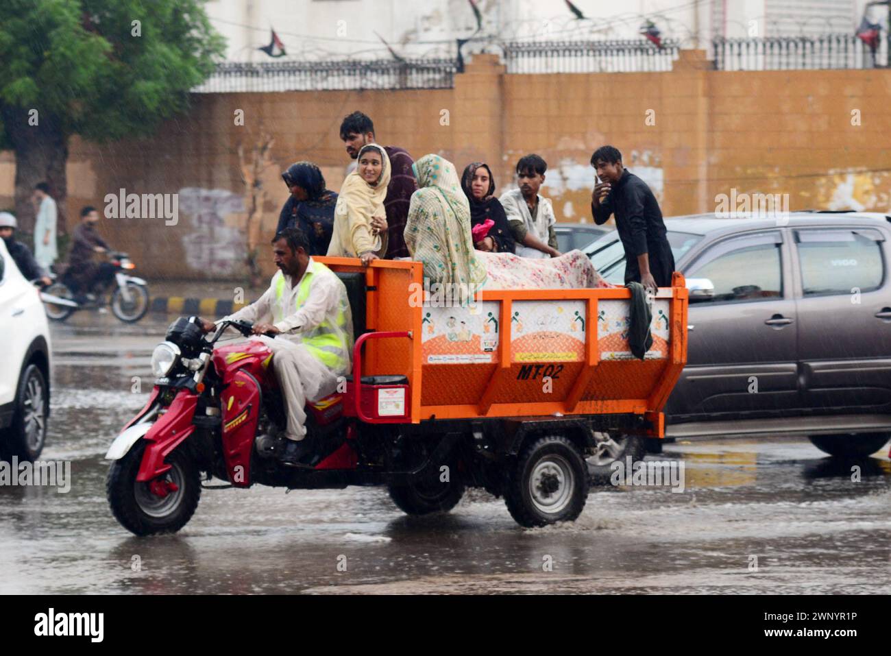 Karachi. 1er mars 2024. Des gens voyagent sur un tricycle à moteur sous la pluie à Karachi, au Pakistan, le 1er mars 2024. Au moins 36 personnes ont été tuées et 41 autres blessées dans différentes pluies et chutes de neige qui ont déclenché des incidents au Pakistan alors que de fortes pluies ont balayé le pays du 27 février au 3 mars, a déclaré l'Autorité nationale pakistanaise de gestion des catastrophes (NDMA). Les défunts comprenaient 21 enfants, neuf hommes et six femmes, a mentionné la NDMA dans un rapport de situation publié dimanche soir. Crédit : Str/Xinhua/Alamy Live News Banque D'Images