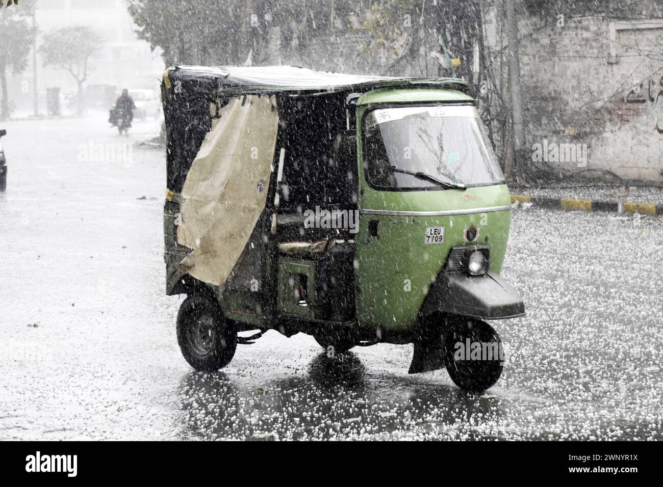 Lahore. 2 mars 2024. Un pousse-pousse automobile court dans la tempête de grêle Lahore, au Pakistan, le 2 mars 2024. Au moins 36 personnes ont été tuées et 41 autres blessées dans différentes pluies et chutes de neige qui ont déclenché des incidents au Pakistan alors que de fortes pluies ont balayé le pays du 27 février au 3 mars, a déclaré l'Autorité nationale pakistanaise de gestion des catastrophes (NDMA). Les défunts comprenaient 21 enfants, neuf hommes et six femmes, a mentionné la NDMA dans un rapport de situation publié dimanche soir. Crédit : Sajjad/Xinhua/Alamy Live News Banque D'Images