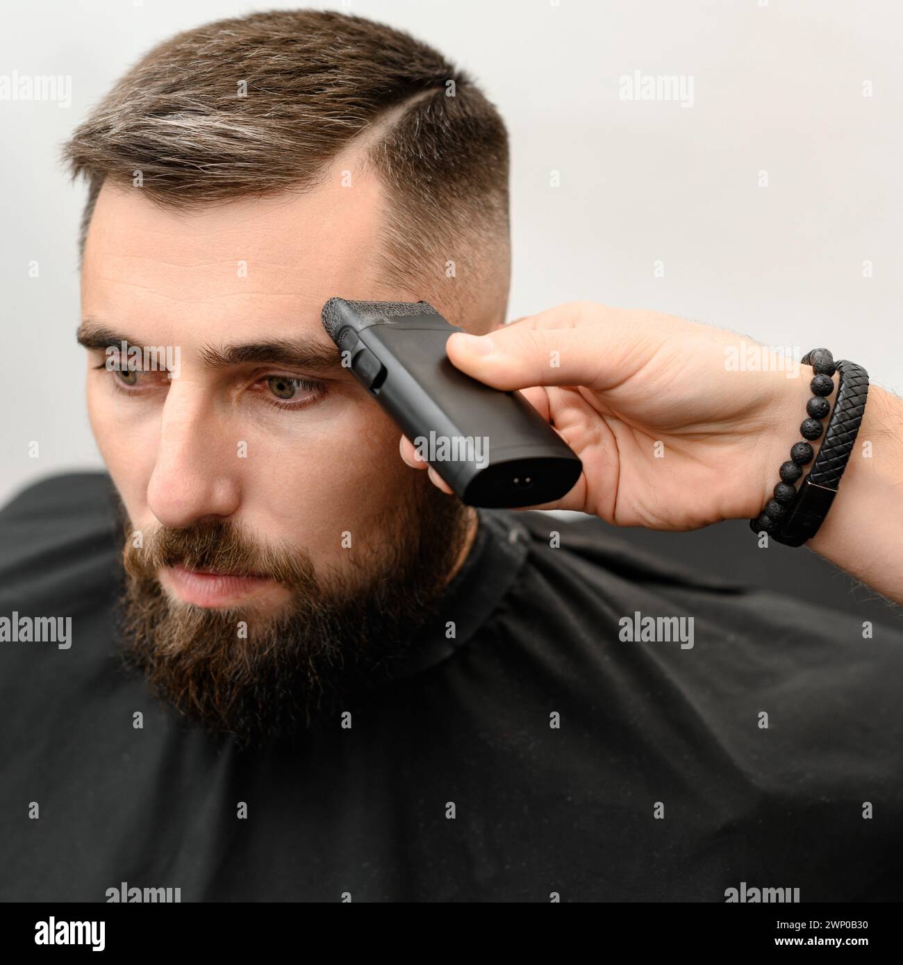 Barber rase la tempe avec une tondeuse sans fil lors d'une courte coupe de cheveux sur les côtés de la tête. Banque D'Images