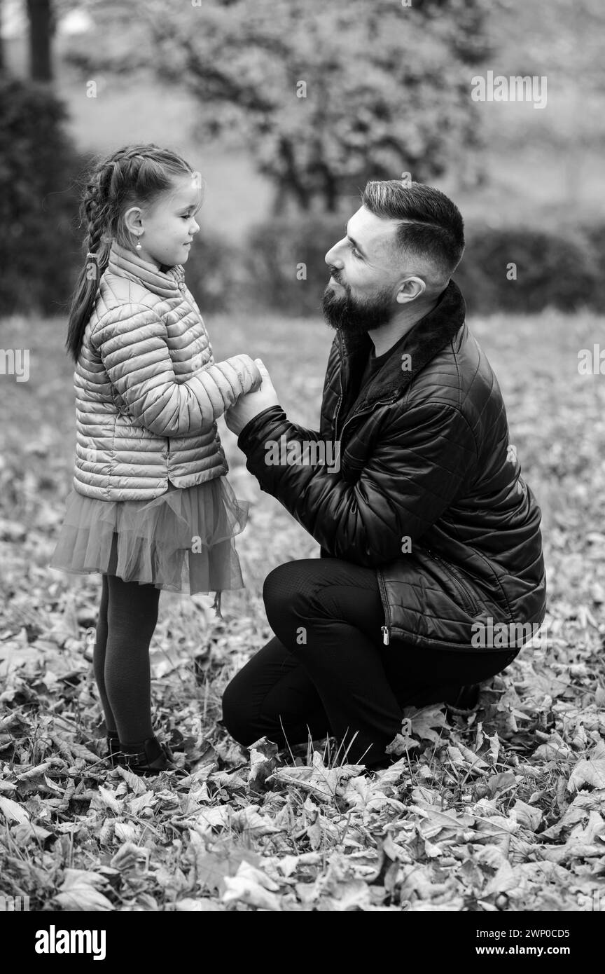 Portrait de papa avec fille en automne noir et blanc parc avec des feuilles jaunes, parentalité. Banque D'Images