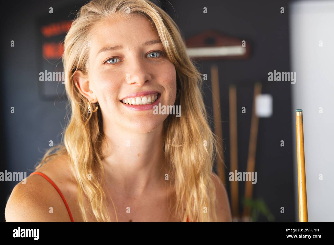 Jeune femme caucasienne aux cheveux blonds et un sourire amical se tient à l'intérieur Banque D'Images