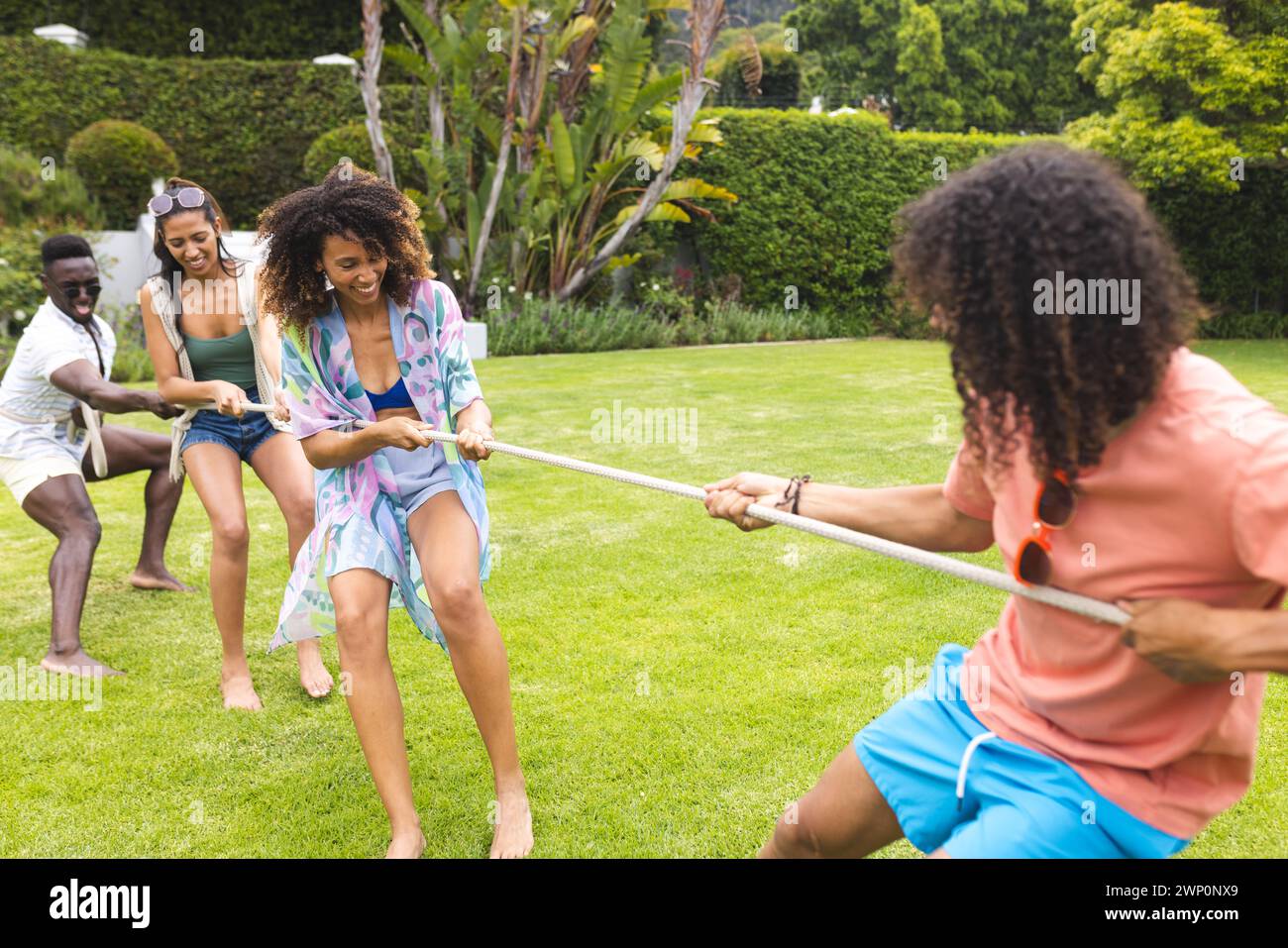 Divers groupes d'amis apprécient un jeu de remorqueur de guerre par une journée ensoleillée en plein air Banque D'Images