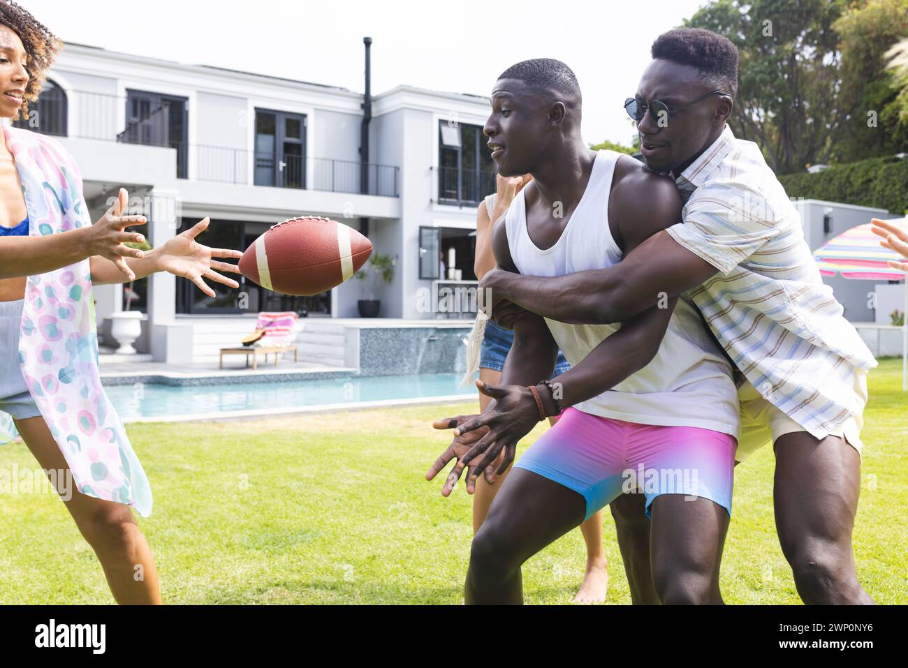 De jeunes hommes afro-américains jouent à la capture avec un ballon de football, une femme biraciale rejoint le plaisir Banque D'Images