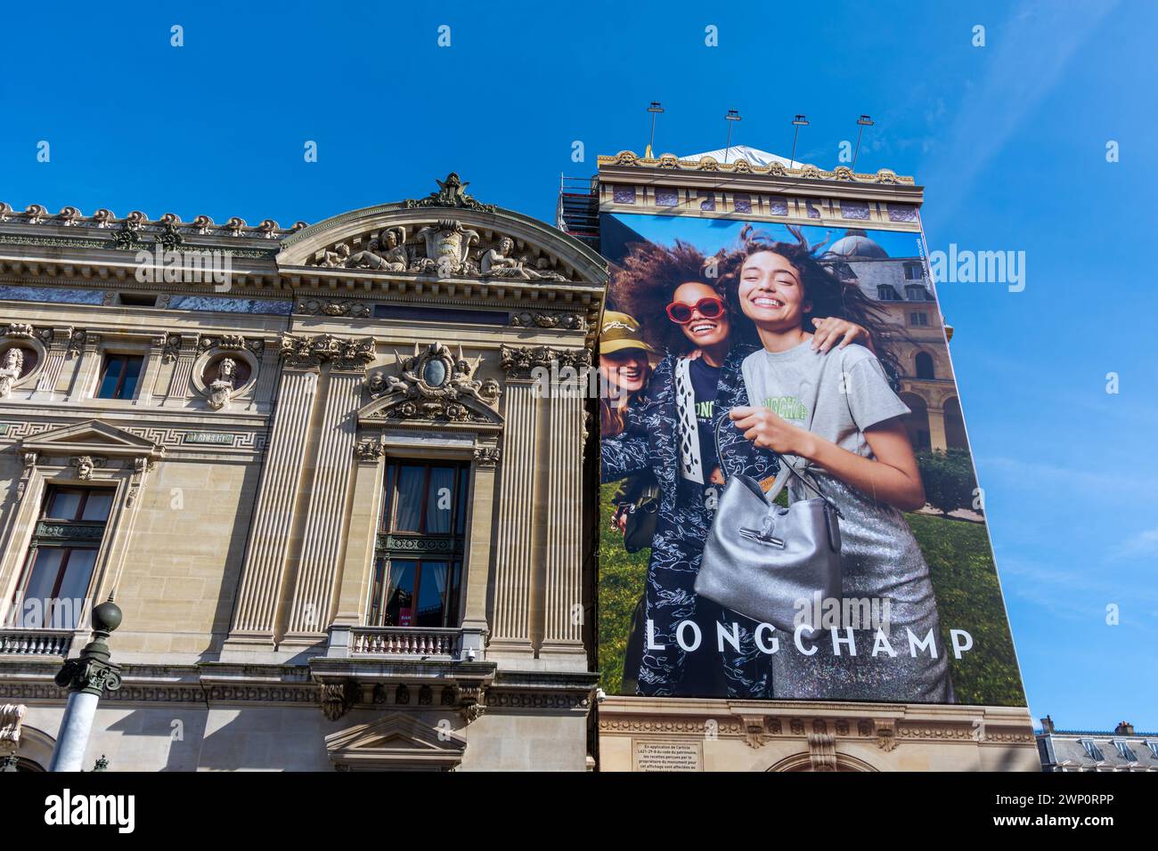 Panneau publicitaire pour Longchamp couvrant les échafaudages des travaux de restauration de la façade latérale de l’Opéra de Paris (Palais Garnier) Banque D'Images