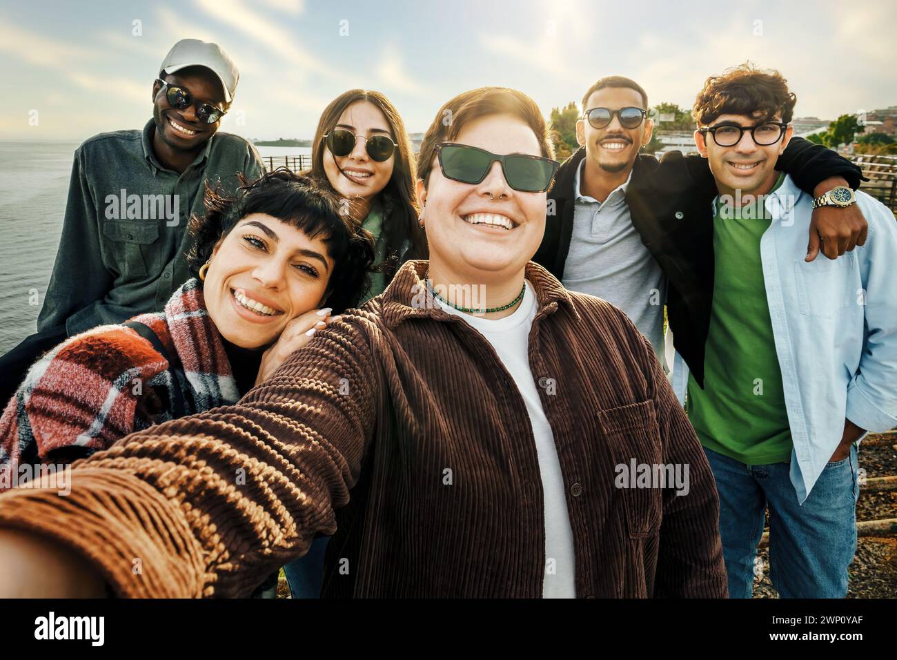 Amis divers prenant un selfie de groupe à l'extérieur - sourires et camaraderie au bord de l'eau - embrassant la diversité et la joie Banque D'Images Amis divers prenant un selfie de groupe à l'extérieur - sourires et camaraderie au bord de l'eau - embrassant la diversité et la joie Banque D'Images