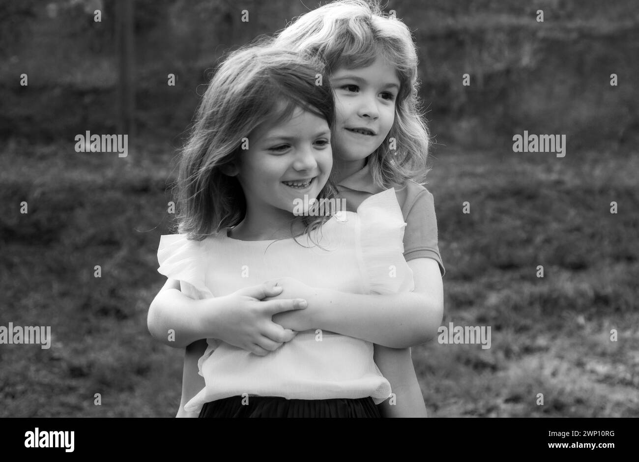 Adorables enfants heureux dehors le jour de l'été, petit garçon embrassant une fille. Adorable petit garçon et fille, amusez-vous et enserrer à l'extérieur. Visage amusant pour les enfants. Banque D'Images