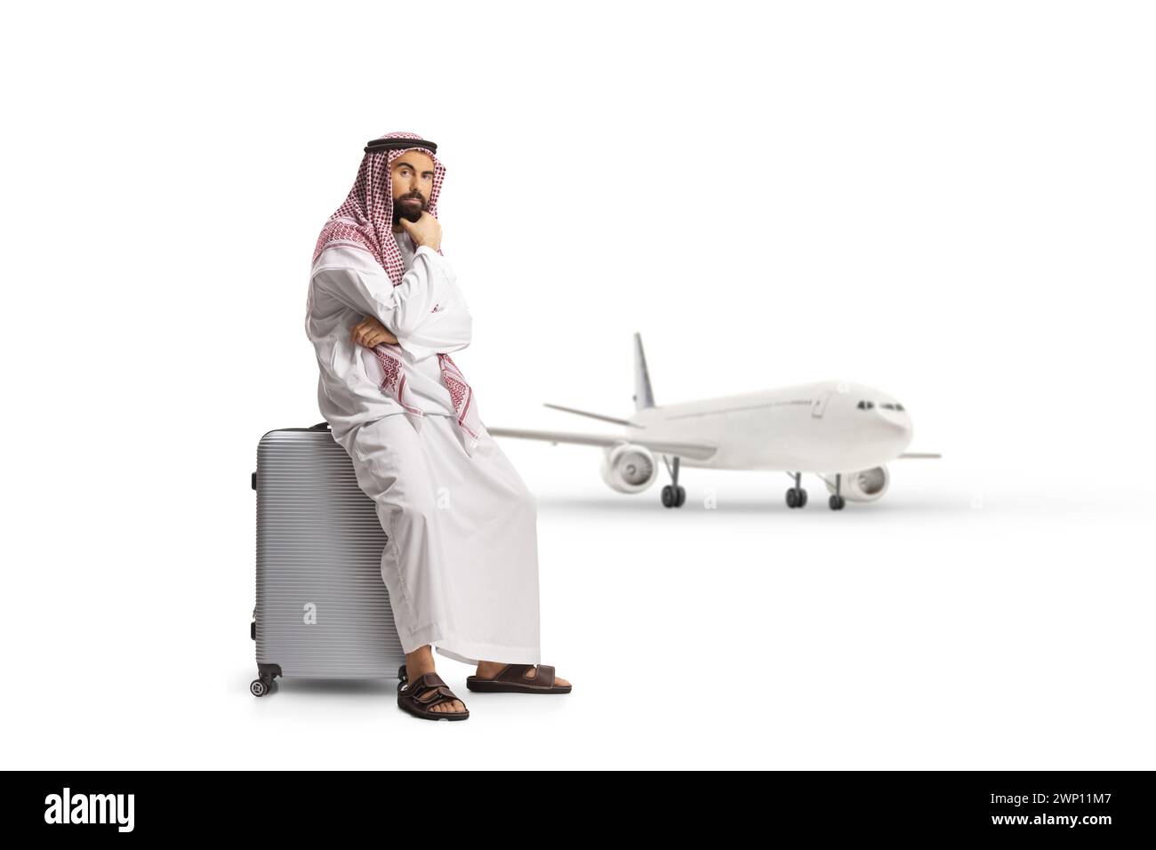Homme arabe saoudien assis sur une valise et pensant, annulé ou un concept de vol retardé isolé sur fond blanc Banque D'Images
