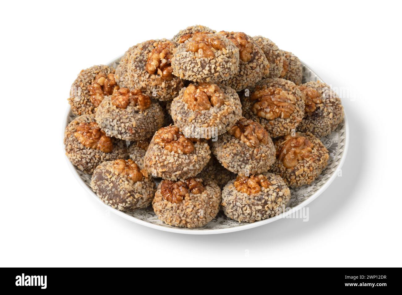 Assiette avec des biscuits Ghoriba marocains frais traditionnels recouverts d'un gros plan de noix isolé sur fond blanc Banque D'Images