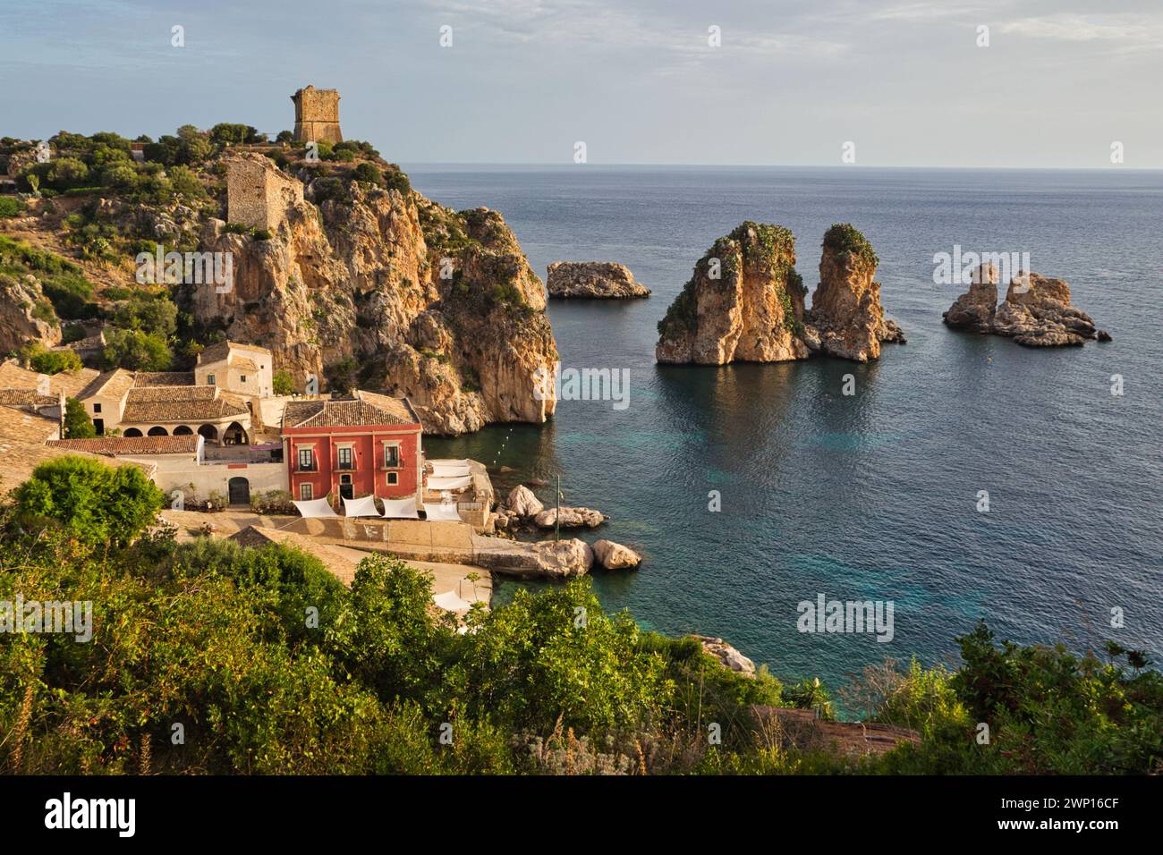 Tonnara di Scopello, Sicile, tôt le matin avec les faraglioni, tours de roche, dans la mer et tour défensive sur la colline Banque D'Images