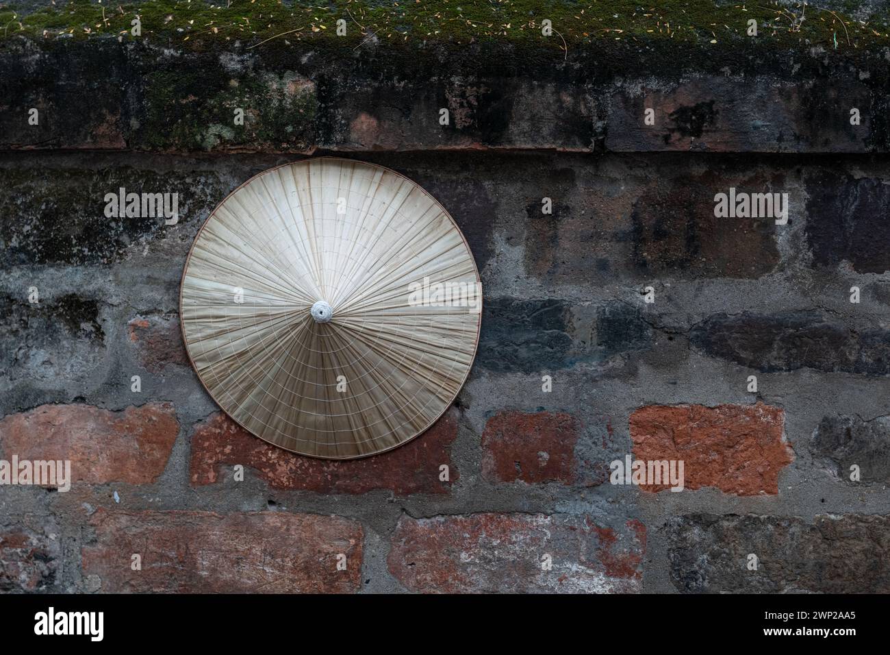 Chapeau de paille conique traditionnel vietnamien accroché sur un mur de briques à Hanoi, dans le nord du Viet Nam. Banque D'Images