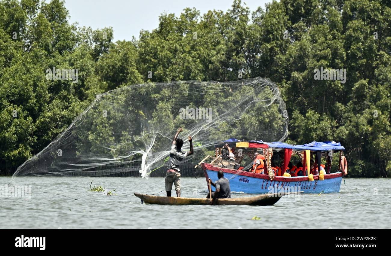 Abidjan, Côte d'Ivoire. 05 mars 2024. Un bateau transportant la reine Mathilde de Belgique passe devant deux jeunes pêcheurs jetant un filet lors d’une excursion en bateau à Grand Lahou, village de pêcheurs le long de la côte d’Ivoire, lors d’une visite royale de travail en Côte d’Ivoire, mardi 05 mars 2024. La Reine est en visite en Côte d’Ivoire en sa qualité d’ambassadrice pour les objectifs de développement durable des Nations Unies (ONU). Crédit : Belga News Agency/Alamy Live News Banque D'Images