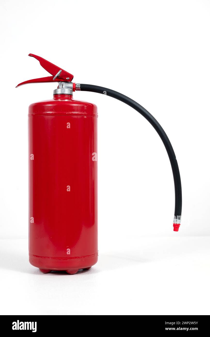 Un extincteur à cylindre rouge avec un tuyau noir, contrastant sur un fond blanc. L'extincteur contient un gaz sous pression et est couramment utilisé Banque D'Images