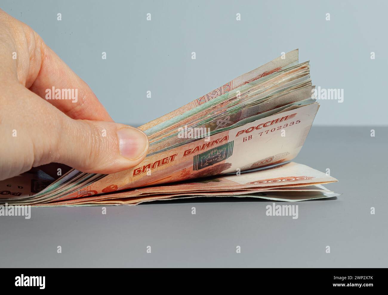 Projet de loi avec une main de papier monnaie en coupures de mille cinq mille roubles russes sur une table grise Banque D'Images