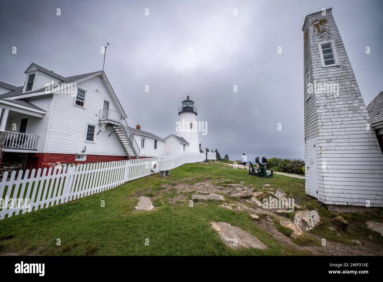 Le phare à Pemaquid Point, Maine avec ciel nuageux au-dessus et les corniches rocheuses massives à l'avant-plan. Banque D'Images