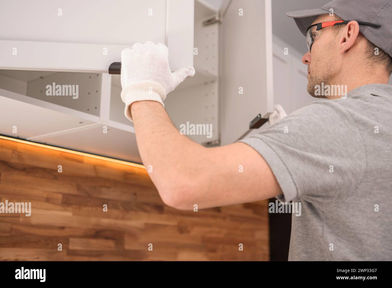 Ébéniste professionnel dans ses années 40 vérifiant sur les garnitures de meubles de cuisine Banque D'Images