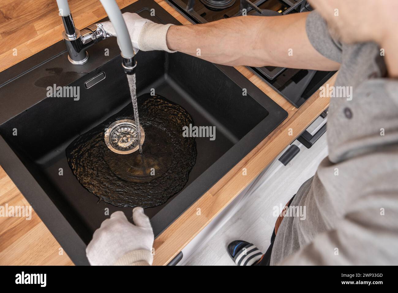 Technicien en plomberie installant un évier de cuisine et un robinet. Vérification de l'alimentation en eau. Banque D'Images