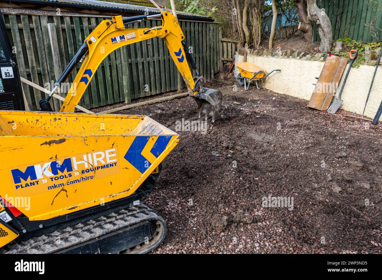 Travaux de construction avec une petite excavatrice dans l'allée pour construire une salle de jardin, Écosse, Royaume-Uni Banque D'Images