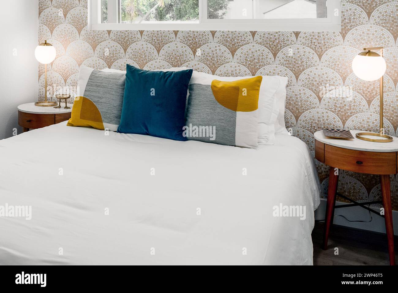 Chambre moderne avec lit confortable, oreillers, tables de nuit et papier peint en mosaïque Banque D'Images