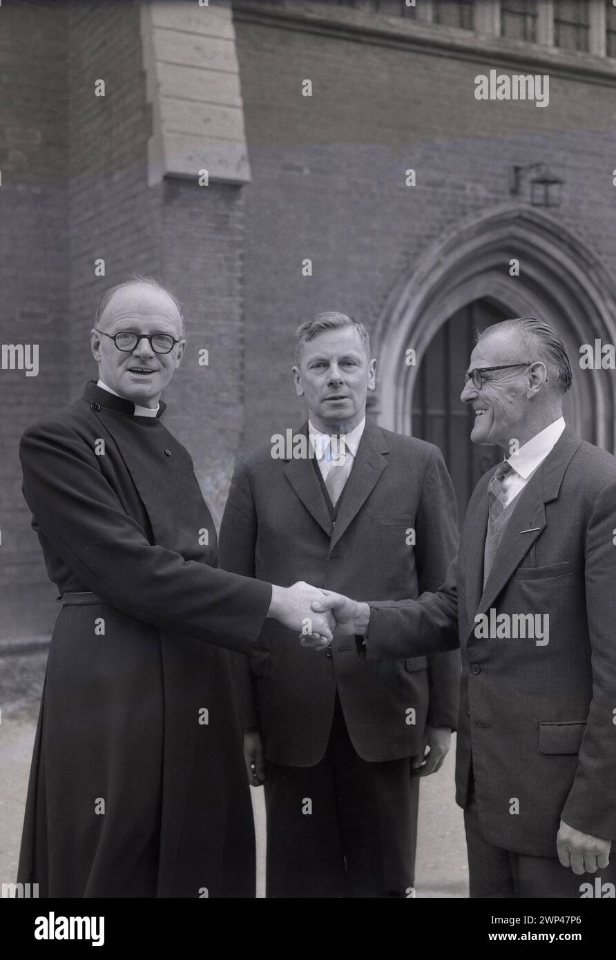 Années 1950, historique, un ecclésiastique anglais, le révérend A. S Wye, devant le presbytère saluant ses nouveaux ecclésiastiques, Oxford, Angleterre, Royaume-Uni. Le XIIIe siècle a vu apparaître des ecclésiastiques, membres d'une congrégation élus par et parmi les paroissiens, pour représenter ceux d'une foi religieuse, les laïcs et assumer la responsabilité du tissu de l'église, de l'administration et d'autres devoirs. Banque D'Images