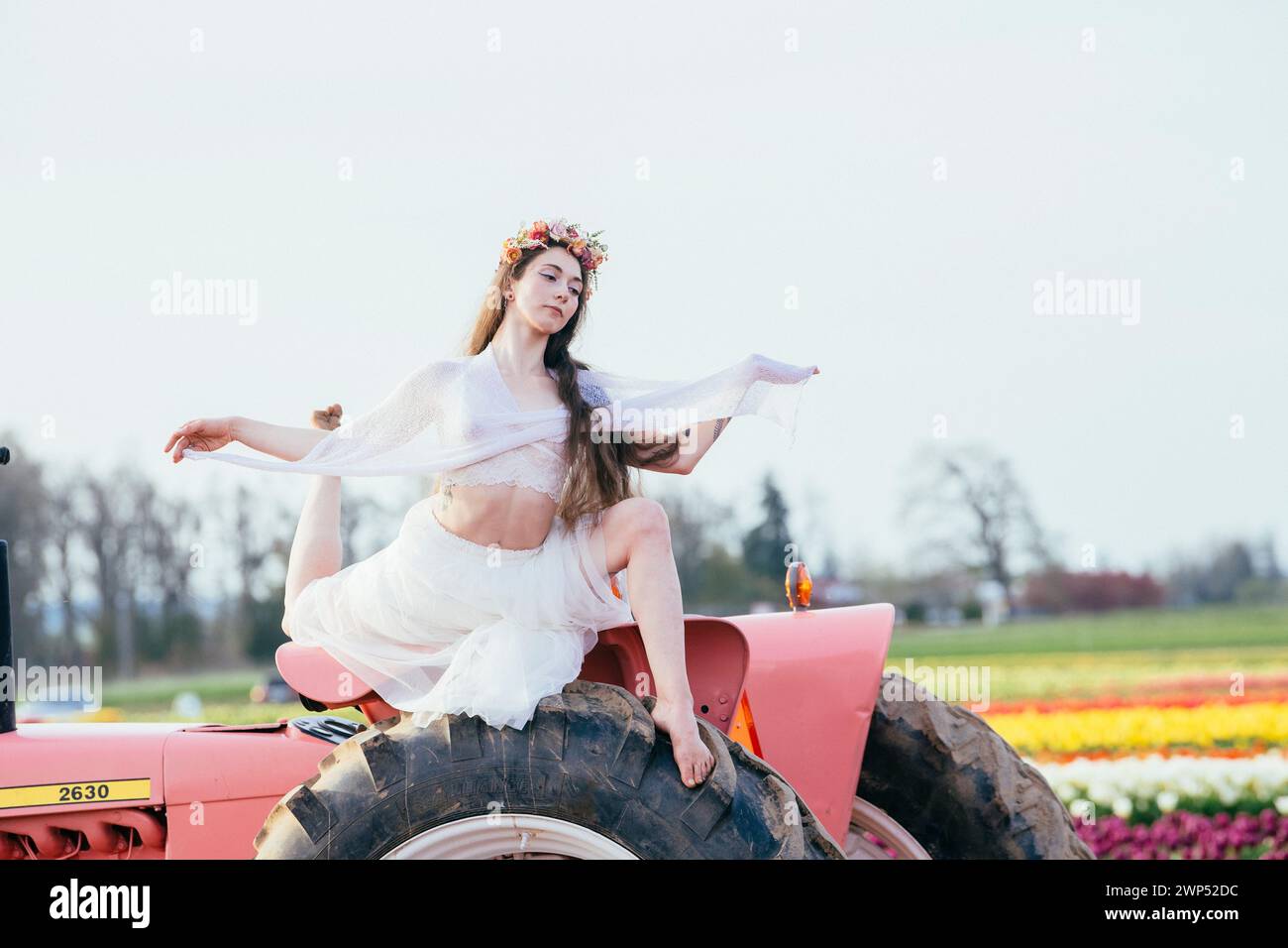 Femme faisant fendre sur le dessus du tracteur debout dans le vaste champ de tulipes Banque D'Images