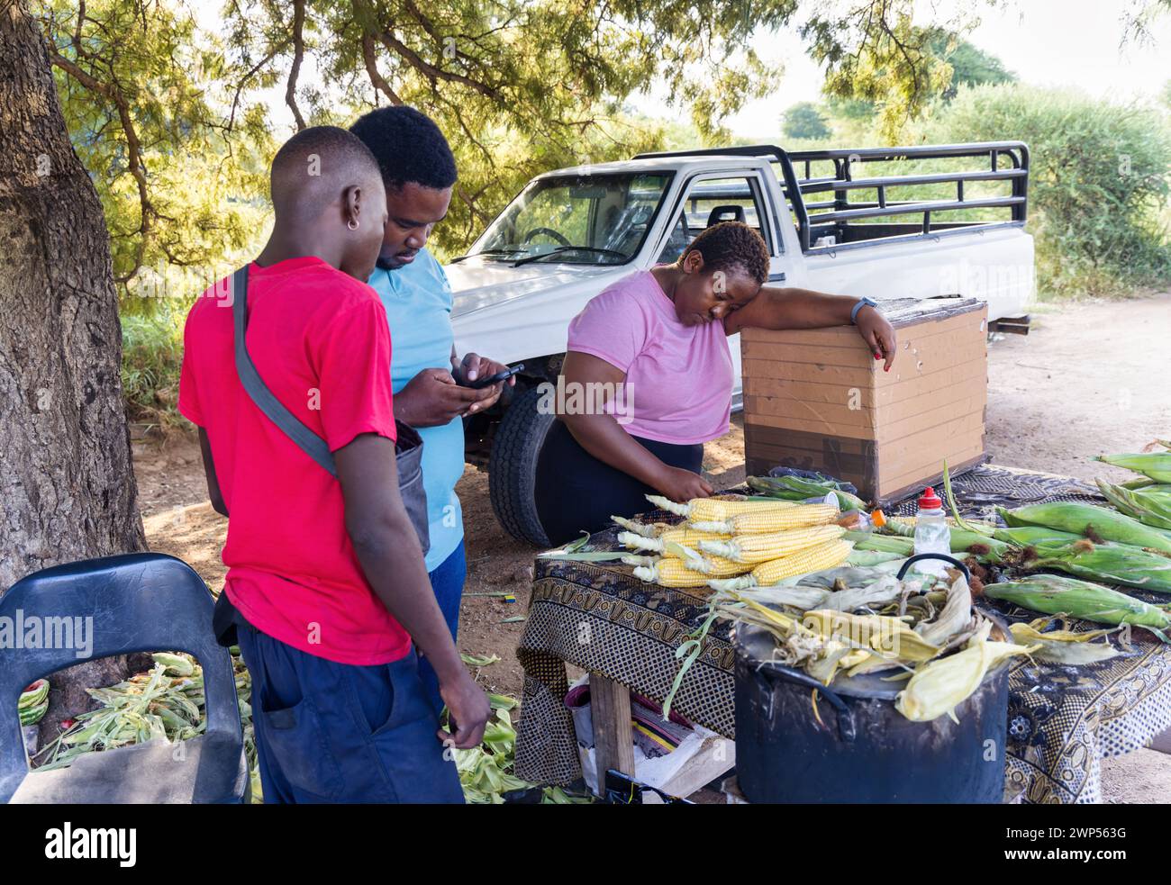 vendeur de rue africain vendant du maïs doux bouilli sur le bord de la route Banque D'Images