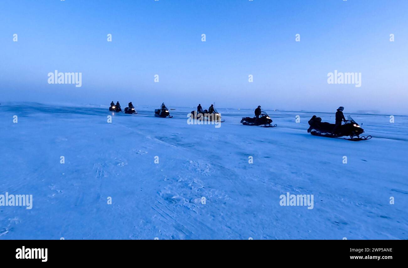 Les Bérets verts de l'armée américaine avec le 19e Groupe des forces spéciales (aéroporté) conduisent des motoneiges à Kotzebue, Alaska, le 27 février 2024. Les Bérets verts doivent voyager dans des conditions austères à destination et en provenance de leur site d'entraînement pendant Arctic Edge 24 (AE24). Le Commandement des opérations spéciales Nord a déployé plus de 400 forces d’opérations spéciales interarmées et alliées dans toute la région panarctique, s’étendant de l’Alaska au Groenland, pendant l’AE24 afin de faire progresser les capacités et la disponibilité opérationnelle du SOF dans des environnements extrêmement froids et de haute latitude. (Photo de l'armée américaine par le sergent d'état-major Brian Darling) Banque D'Images