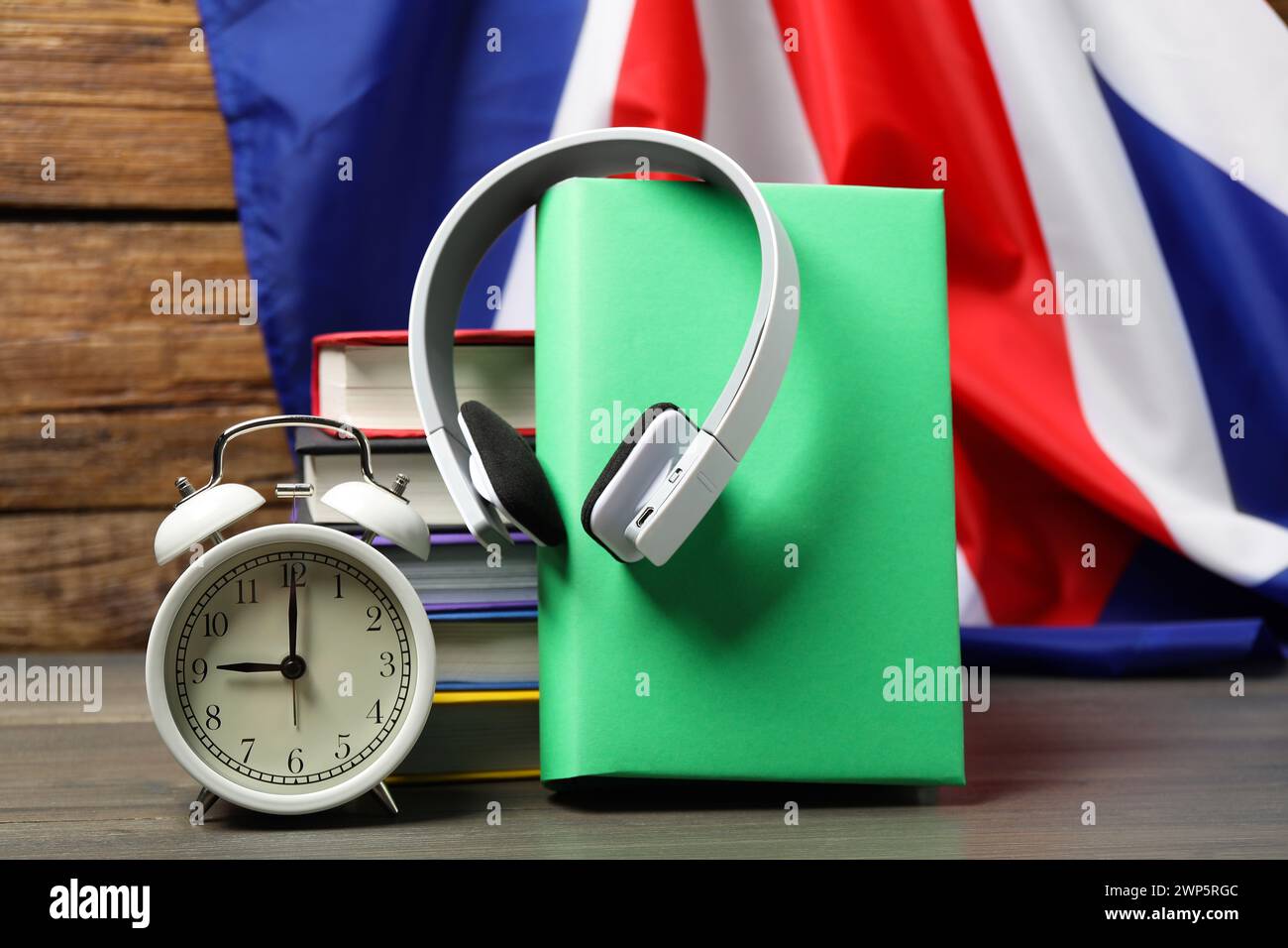 Apprendre une langue étrangère. Différents livres, écouteurs et réveil sur la table en bois près du drapeau du Royaume-Uni Banque D'Images