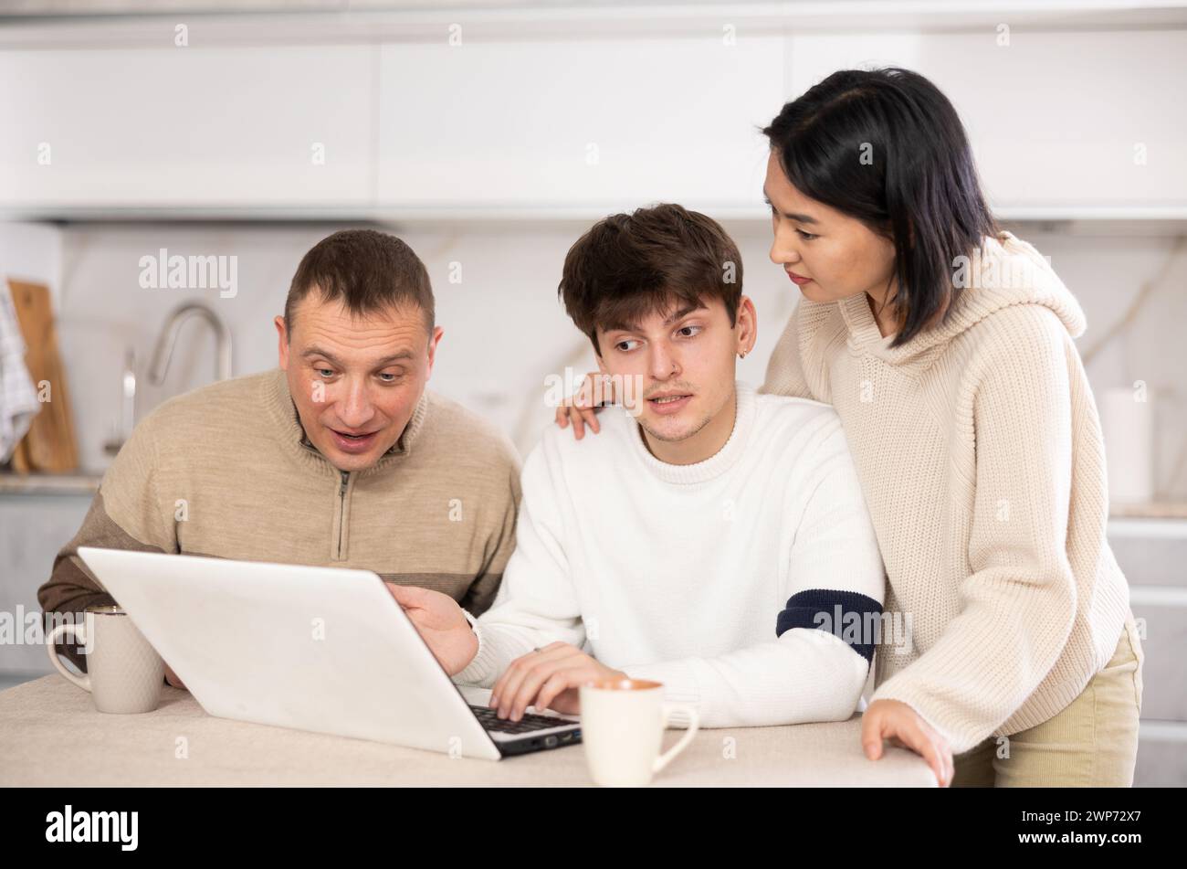 Une famille amicale regarde quelque chose ensemble sur Internet ou des chats vidéo via un ordinateur portable Banque D'Images