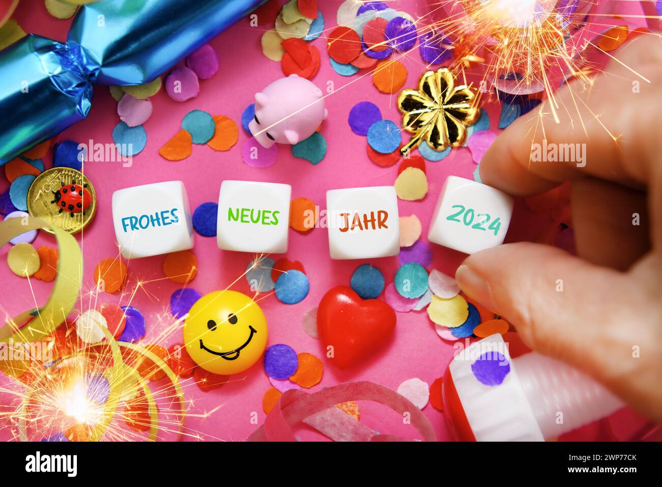 Würfel mit Aufschrift Frohes Neues Jahr 2024 umgeben von Konfetti und Glücksbringern, Symbolfoto Neujahr 2024, Fotomontage Banque D'Images
