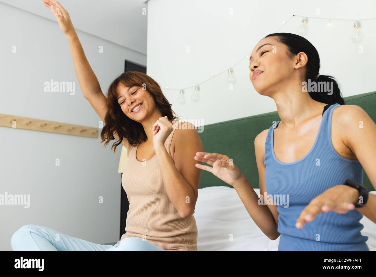 Deux jeunes amis biraciaux dansent joyeusement sur un lit à la maison Banque D'Images