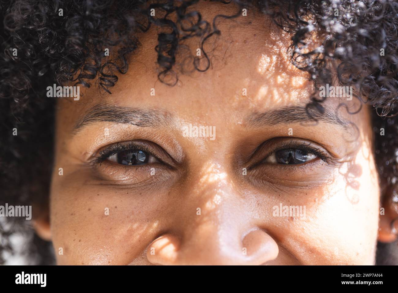 Gros plan d'une femme biraciale aux cheveux bouclés et aux yeux bruns Banque D'Images