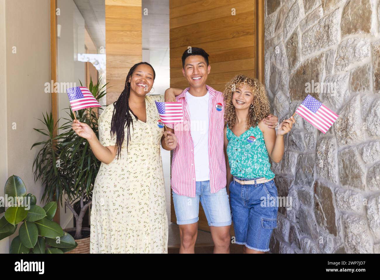 Divers amis tiennent des drapeaux américains à l'entrée de la maison Banque D'Images