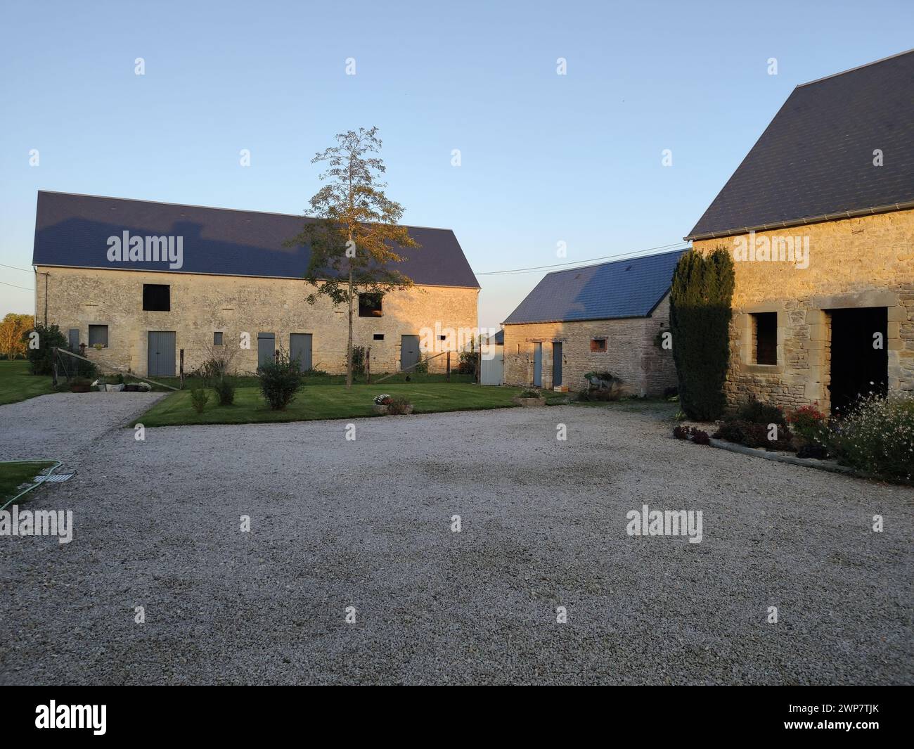 Belle ferme française classique, ancienne architecture en pierre et bois avec une cour bien entretenue. C'est un hôtel rustique confortable. C'est le coucher du soleil Banque D'Images