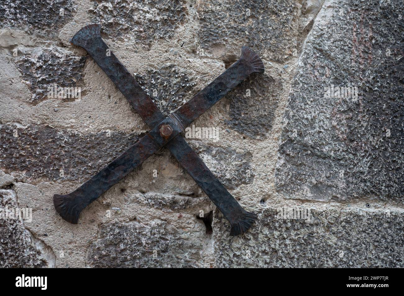 Détail de l'ancienne croix en fer forgé soutenant la façade en pierre d'une ancienne maison médiévale Banque D'Images