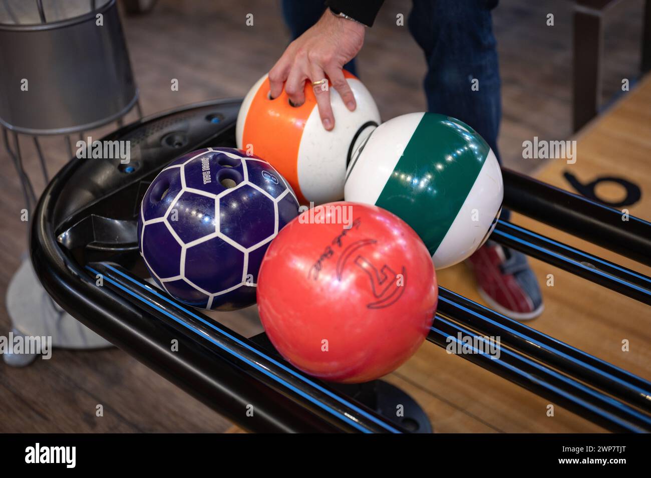 Détail d'une main prenant une boule de bowling de la machine. Banque D'Images