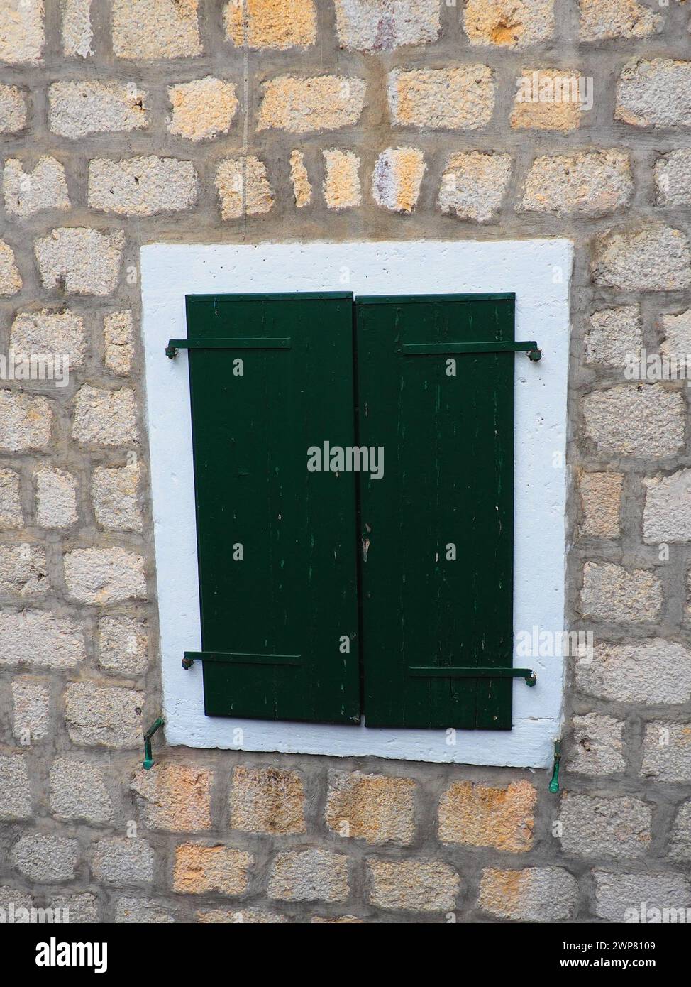 La vieille fenêtre avec des volets verts fermés sur une vieille maison. Texture vintage. Herceg Novi, Monténégro, vieille maison en pierre. Architecture de l'Adriatique Banque D'Images