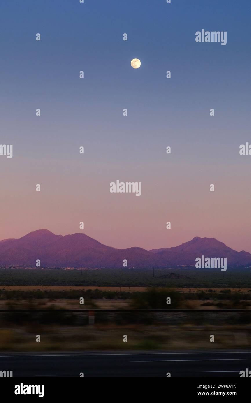 La Lune se levant au-dessus des sommets de montagne pendant le coucher du soleil Banque D'Images La Lune se levant au-dessus des sommets de montagne pendant le coucher du soleil Banque D'Images