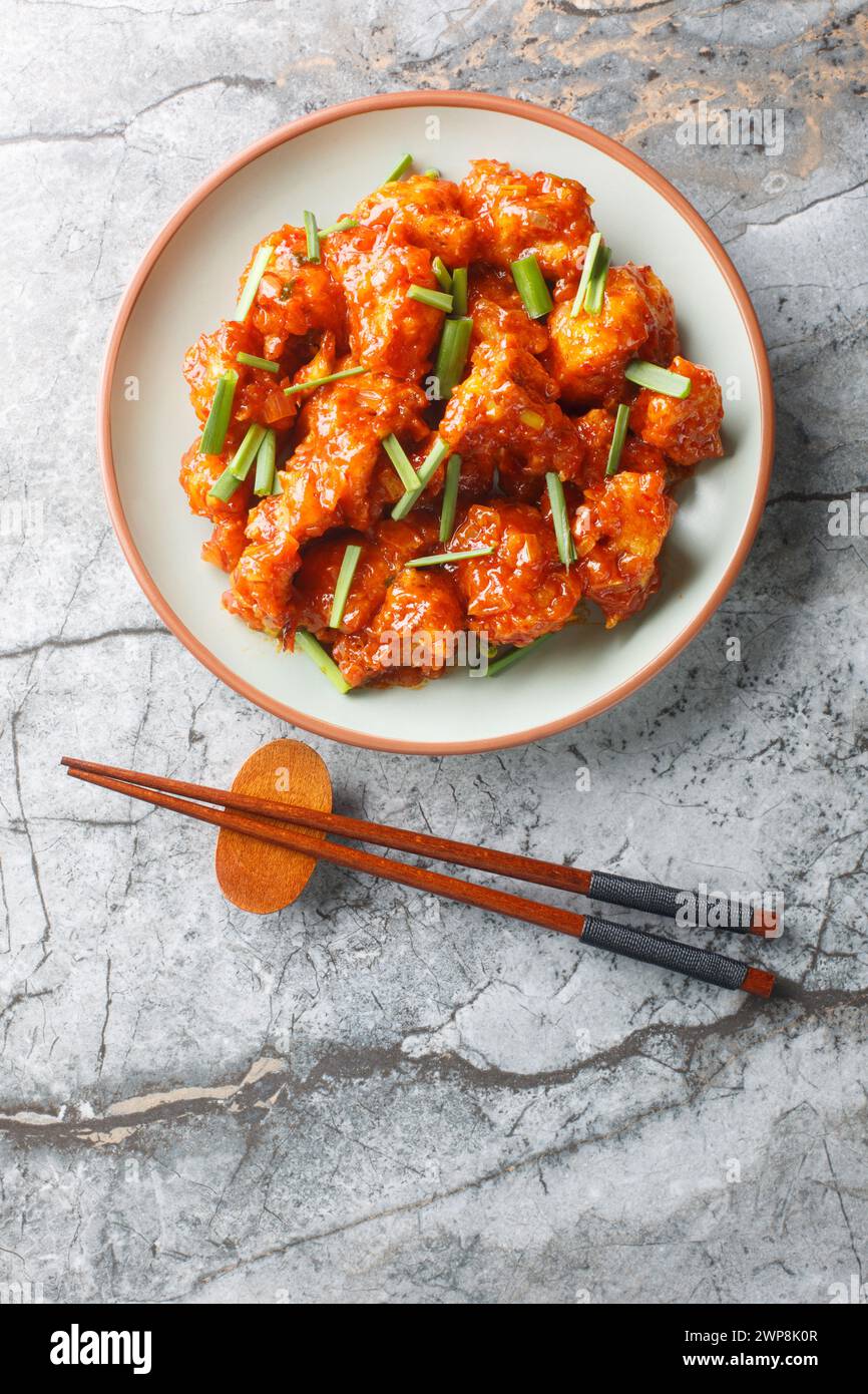 Gobi Mandchourie couple le chou-fleur croustillant avec une sauce indo-chinoise sucrée et acidulée en gros plan sur l'assiette sur la table. Vue de dessus verticale Banque D'Images