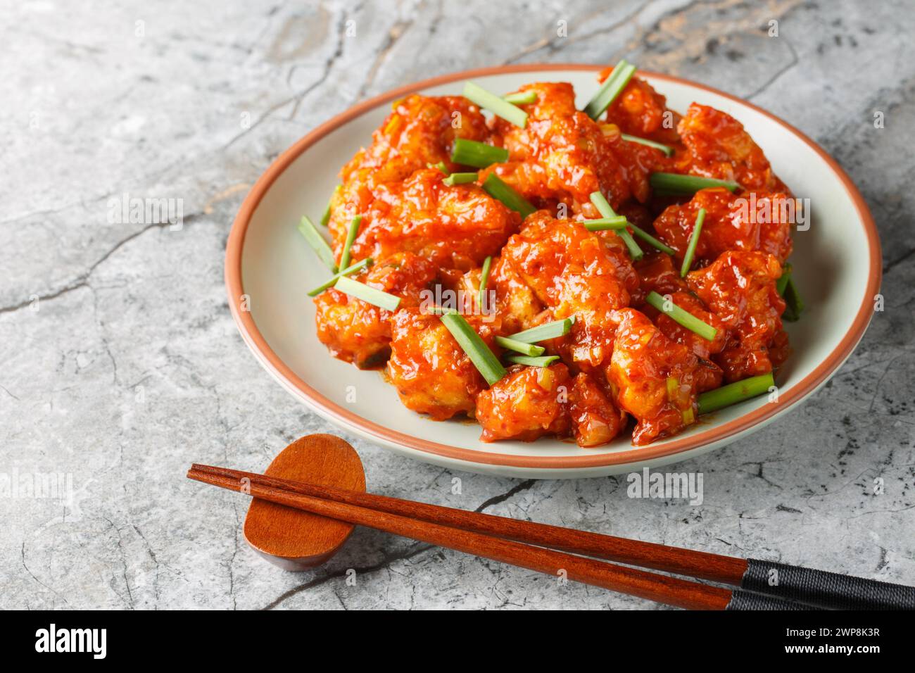 Gobi Manchurian est un apéritif populaire fait avec du chou-fleur frit enrobé de sauce Chili umami en gros plan sur l'assiette sur la table. Horizontal Banque D'Images