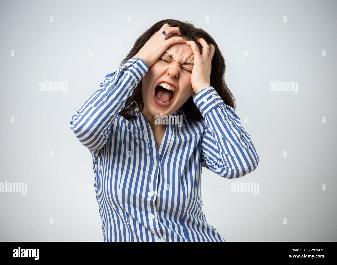 Femme frustrée en colère criant et tenant sa tête, isolée sur fond gris Banque D'Images