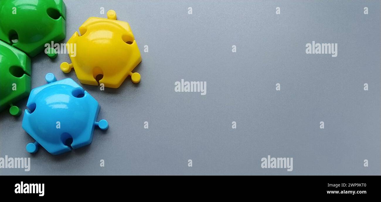 Détails multicolores du concepteur pour enfants sur fond gris. Disques en plastique jaune, vert, bleu pour le développement des compétences de moteur fin de Banque D'Images