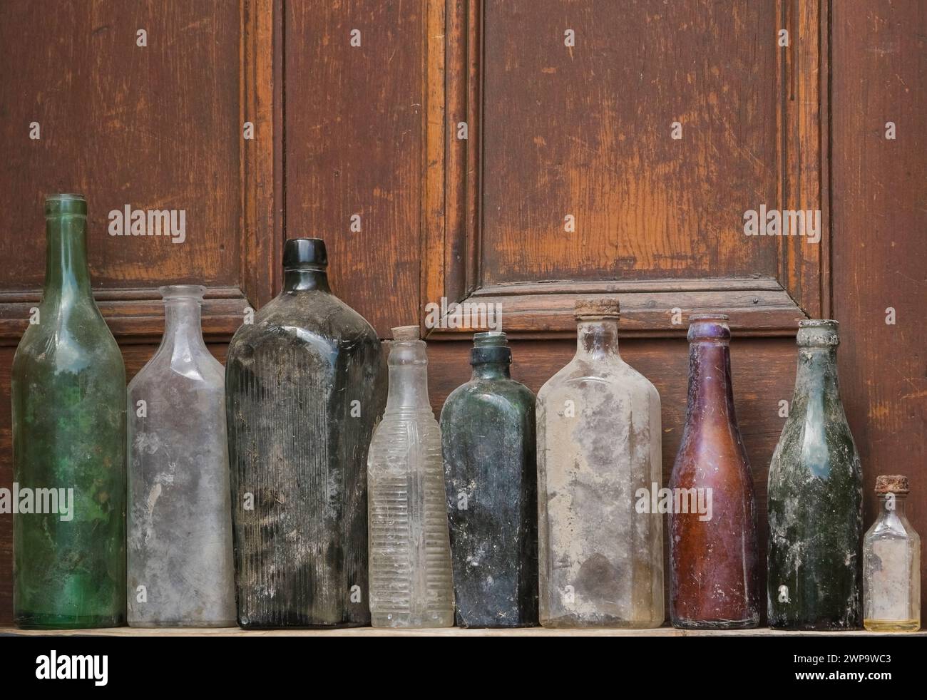 Gros plan de vieilles bouteilles en verre assorties découvertes sur un fond de porte en bois. Banque D'Images