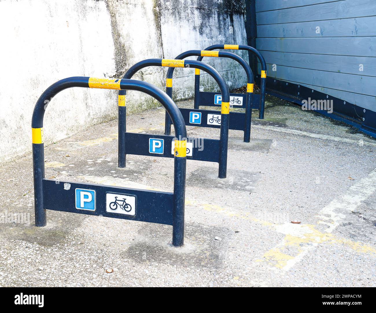 Place de parking pour vélos avec des supports et des autocollants d'information en bleu avec du ruban de marquage jaune Banque D'Images