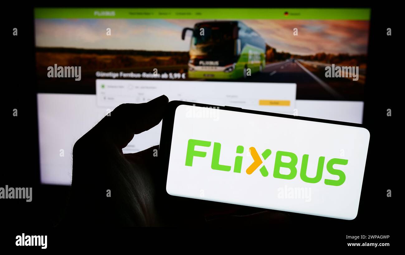 Personne tenant un smartphone avec le logo de la compagnie allemande de transport par bus longue distance FlixBus en face du site Web. Concentrez-vous sur l'affichage du téléphone. Banque D'Images
