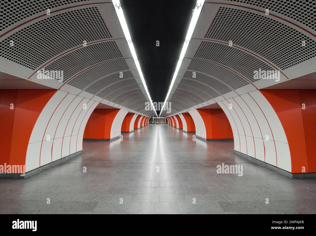 Station de métro moderne blanche et orange. Vue en perspective du hall vide entre les quais. Vue symétrique de l'allée de la station souterraine en forme d'arc. Banque D'Images
