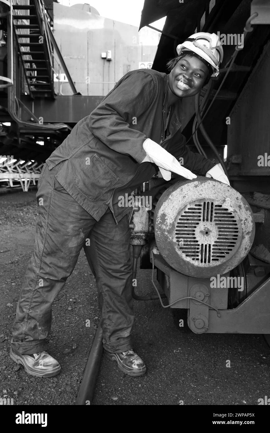 Ouvrier soudant des tuyaux dans la rue sous un camion à benne basculante Banque D'Images