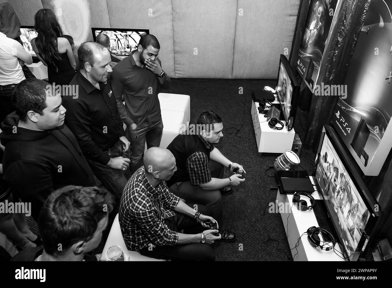 Groupe de personnes jouant à des jeux tout en regardant la télévision Banque D'Images
