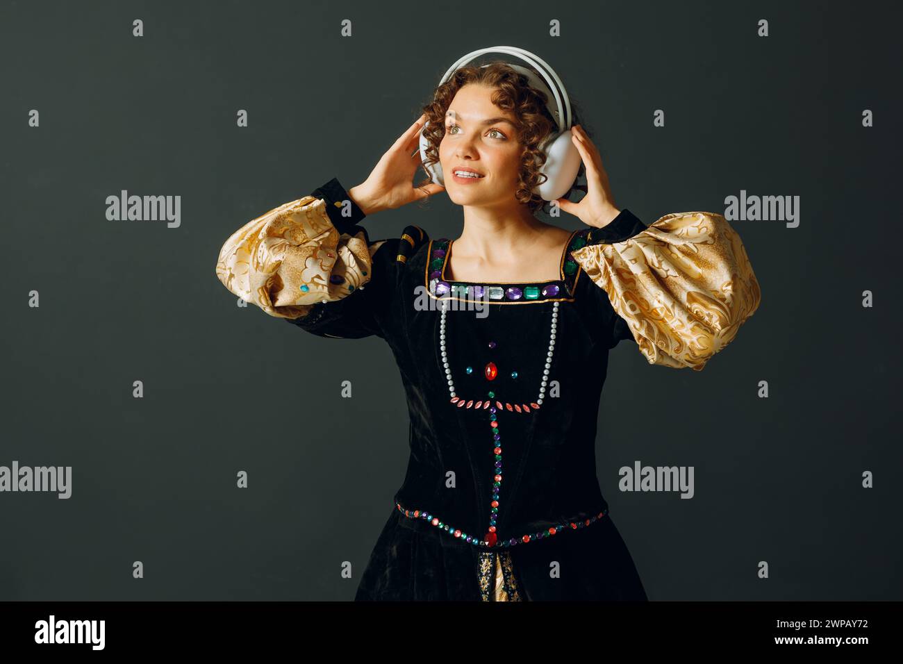 Portrait d'une jeune femme aristocratique avec des écouteurs sur la tête et vêtue d'une robe médiévale écoute de la musique classique Banque D'Images