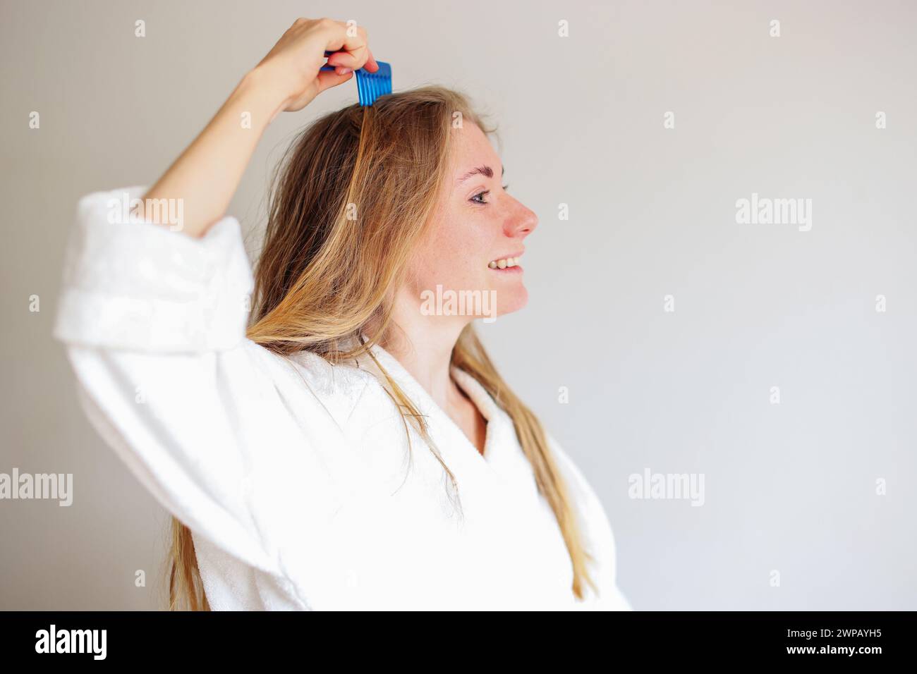 fille blonde peignant les cheveux mouillés. Concept de soins capillaires. Banque D'Images